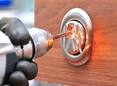 Imagen de un cerrajero utilizando una radial recta para perforar una cerradura
